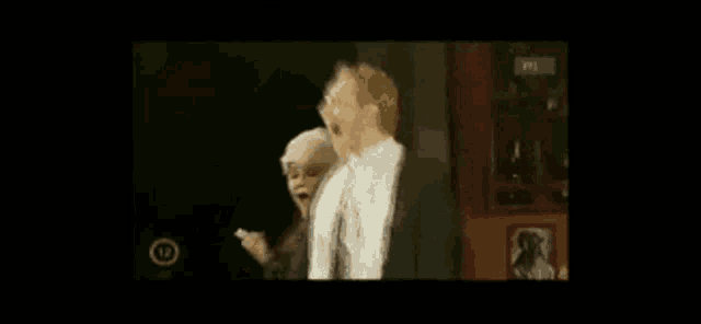 a man and a woman are standing next to each other in a dark room in a video .
