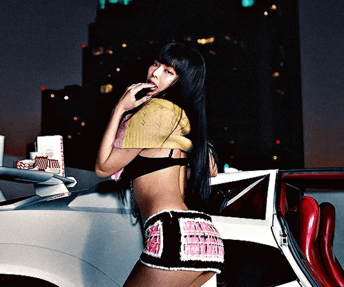 a woman in a crop top and shorts stands in front of a silver car