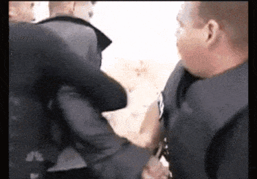 a group of police officers are holding a man in a handcuffs