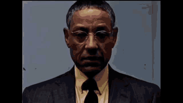 a man in a suit and tie is wearing glasses and a yellow shirt .
