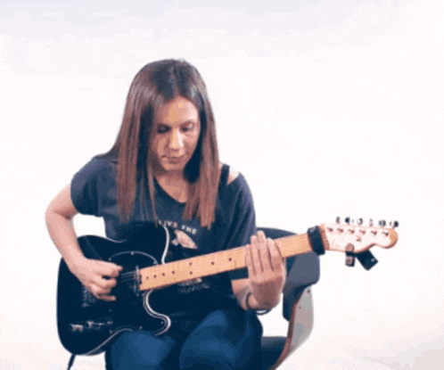 a woman playing an electric guitar with a shirt that says " live the cat "