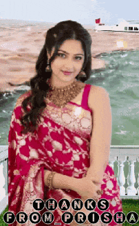 a woman in a red saree is standing in front of a body of water and says thanks from prisha .