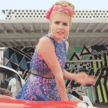 a woman in a blue and pink dress is standing in front of a building with the letter a on it