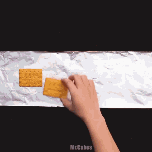 a person is putting aluminum foil on top of a row of biscuits that have the letters gmc on them
