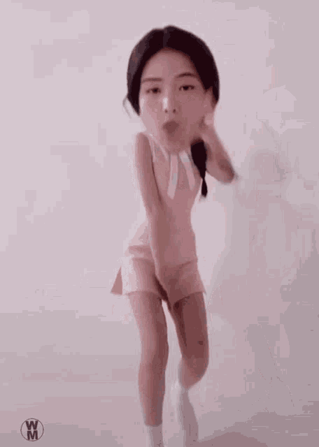 a girl in a pink dress is dancing in front of a white background