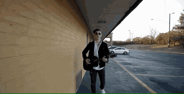 a man walking down a hallway with a guitar in his hand