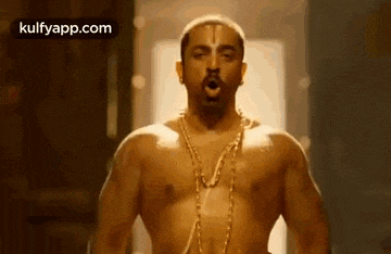 a shirtless man wearing a gold chain around his neck is standing in a room .