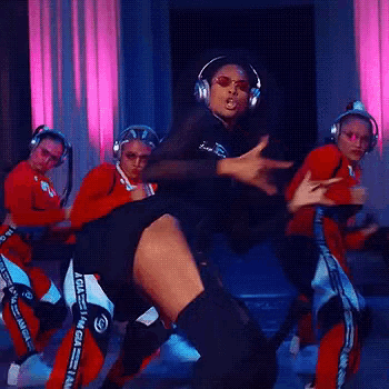 a woman wearing headphones is dancing with a group of dancers in a room .