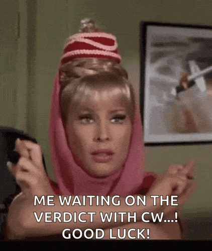 a woman wearing a pink scarf and a red hat is waiting on the verdict with good luck .