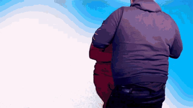 a man in a purple hoodie is standing in front of a blue sky