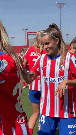 a female soccer player wearing a red and white striped shirt that says herbalife