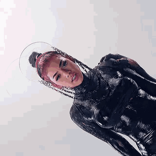 a woman with pink hair is covered in black paint and wearing a clear headband