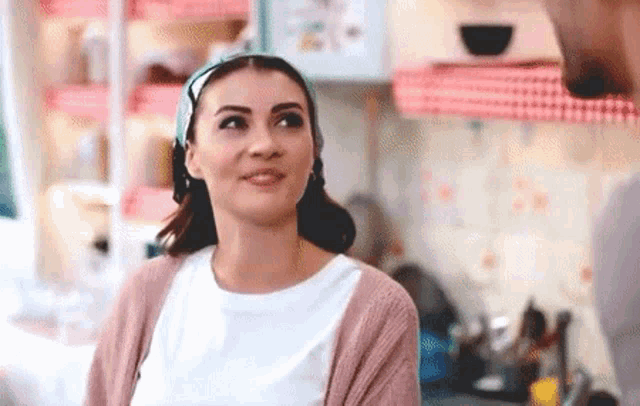 a woman in a pink cardigan is standing in a kitchen with a man .