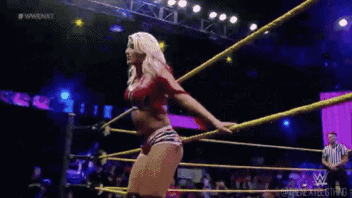 a woman is falling into a wrestling ring while a referee looks on .