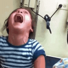 a little girl is screaming in a doctor 's office while sitting in a chair .