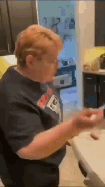 a woman is sitting at a table in a kitchen holding a spoon .