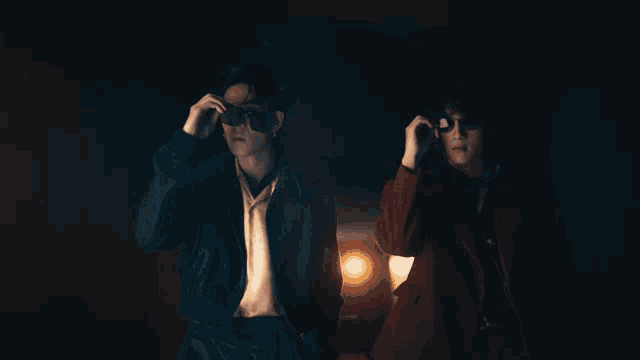 a man in a blue jacket stands next to another man in a red coat