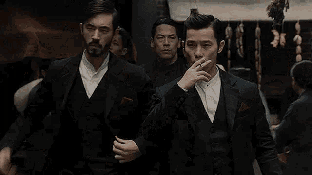 a group of men in suits are standing next to each other in a crowded street .
