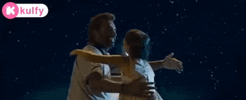 a man and woman are hugging in front of a full moon in the night sky .