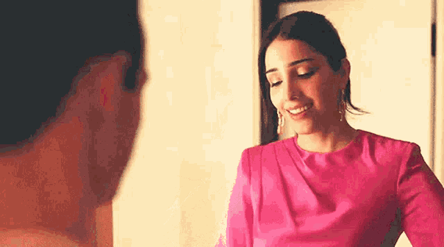a woman in a pink dress is standing next to a man and smiling .
