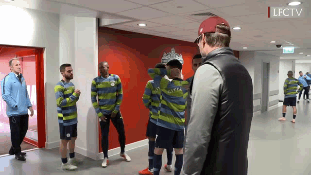 a group of soccer players are standing in a hallway with the letters lfctv visible