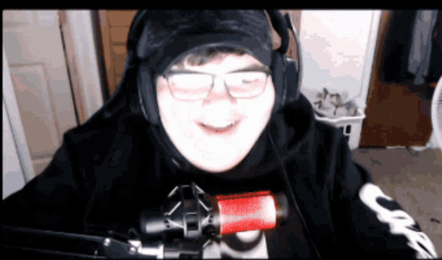 a man wearing headphones and glasses is smiling in front of a microphone