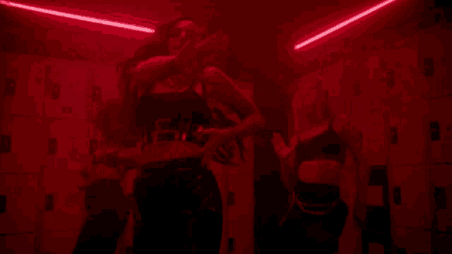 a woman in a black top is dancing in a dark room with red lights