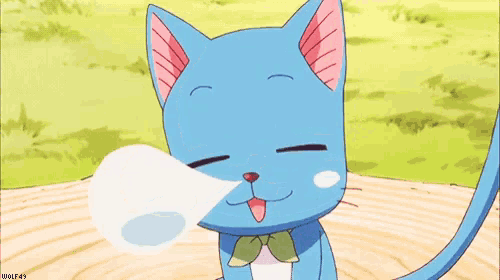 a blue cat with a bow on its neck is sitting on a wooden table and blowing a bubble .
