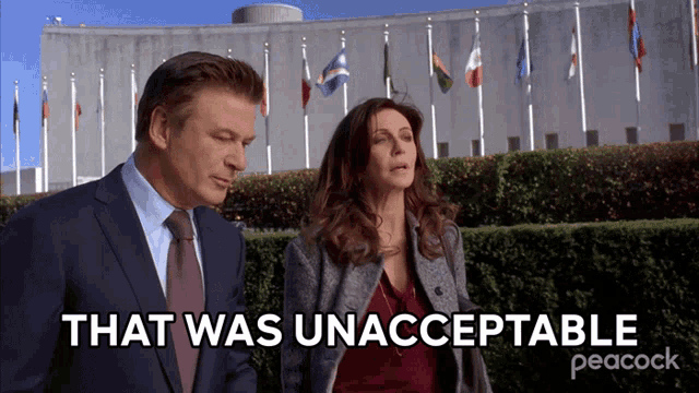 a man and a woman standing in front of a building that says that was unacceptable peacock