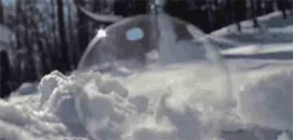 a soap bubble is floating in the snow with the sun shining through it