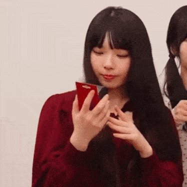 a woman is holding a red cell phone in her hands .