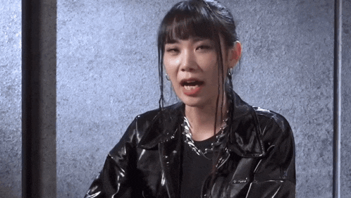 a woman is wearing a black leather jacket and a black shirt .
