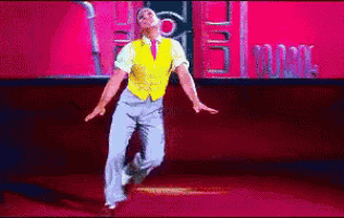 a man in a yellow vest is dancing in front of a pink wall
