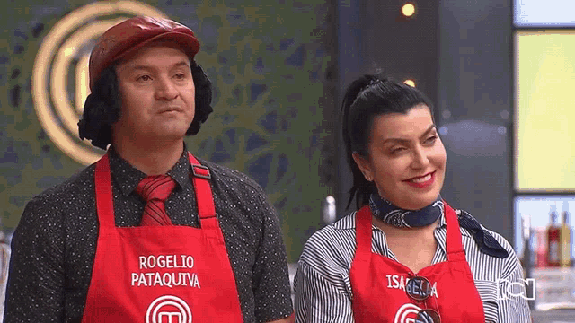 a man and a woman are standing next to each other wearing red aprons .
