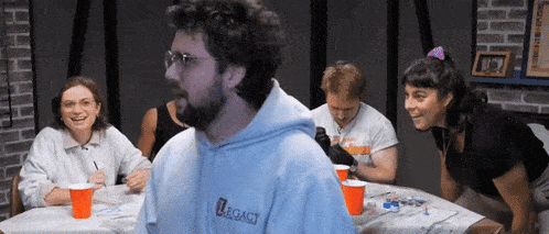 a group of people are sitting around a table with a man wearing a hoodie that says legacy on it