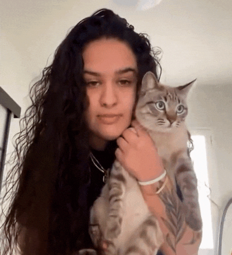 a woman with long hair is holding a cat