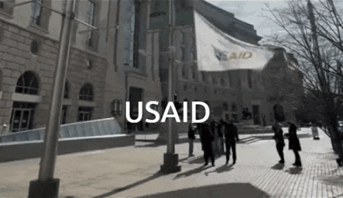 a group of people standing in front of a building that says usaid