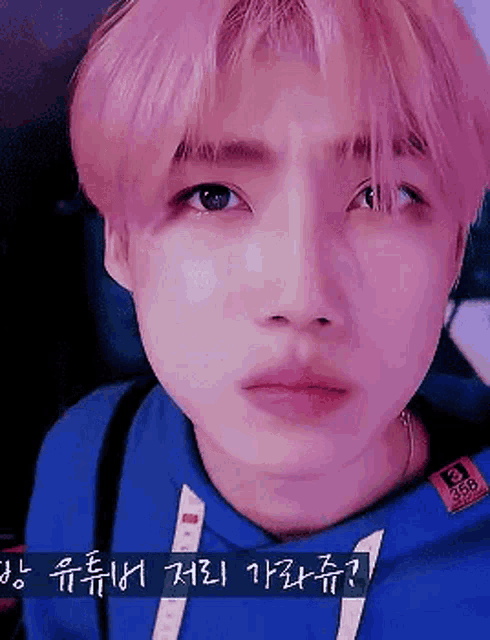 a close up of a person with pink hair wearing a blue hoodie .