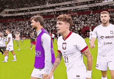 a soccer player with the number 21 on his jersey walks on the field