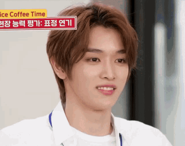 a young man in a white shirt is smiling in front of a sign that says ice coffee time .