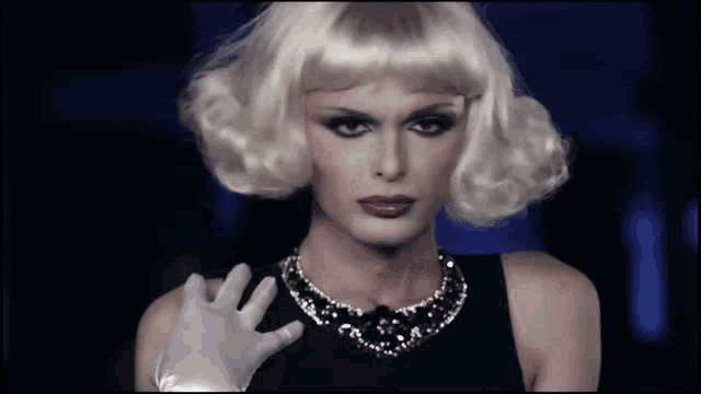 a woman with blonde hair wearing a necklace and a black dress