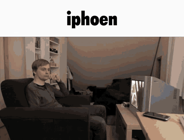 a man sits in a chair in front of a tv with the word iphoen on the bottom