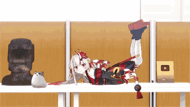 an anime girl is laying on a shelf next to a cat and a statue