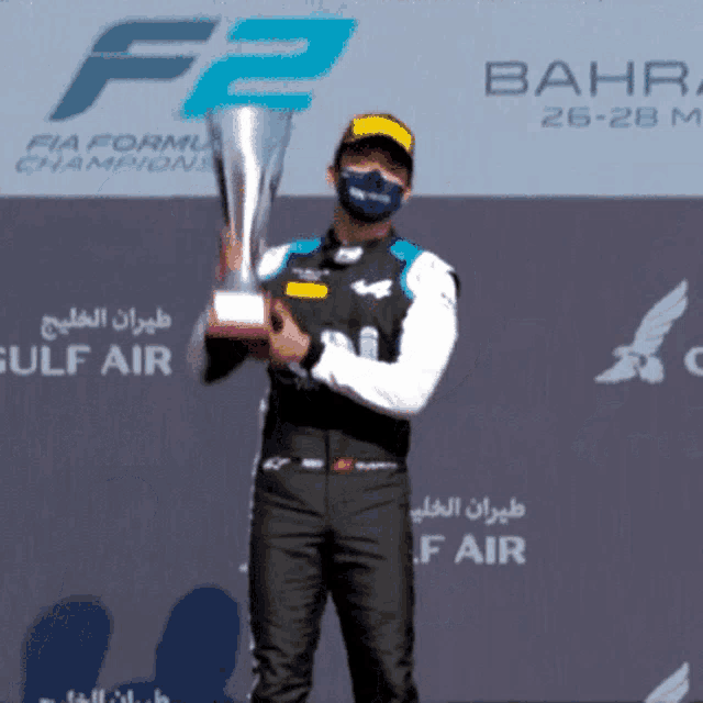 a man wearing a mask holds a trophy in front of a sign that says bahr