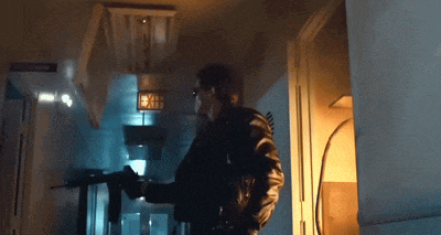 a man is holding a gun in a dark room with a sign that says exit