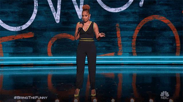 a woman stands on a stage holding a microphone with the hashtag bring the funny
