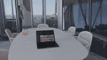 a laptop sits on a table in front of a glass of wine