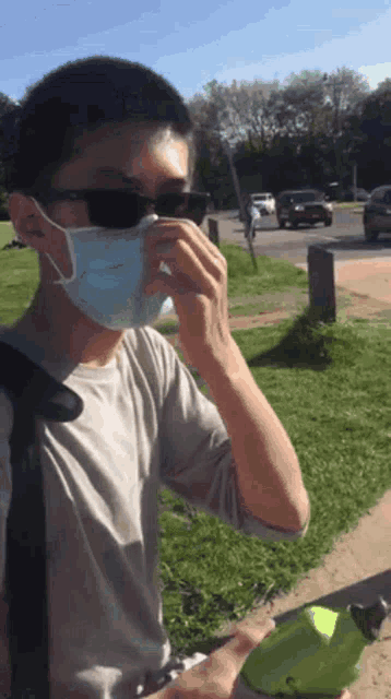 a man wearing a face mask and sunglasses is holding a green bottle