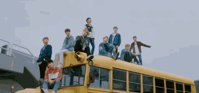 a group of people sitting on top of a yellow school bus with a stop sign