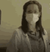 a woman wearing a mask is standing in front of a wall .